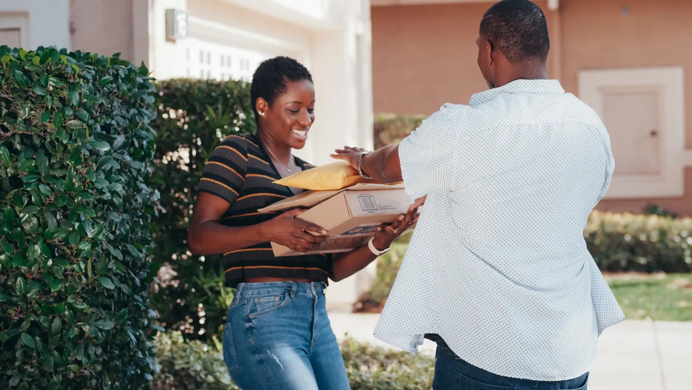 A courier handing parcels to a customer at her door